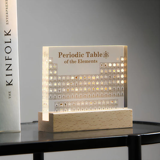 Josh & Tate - Elementa Periodic Table - Light-up periodic table of elements on a wooden base with a book titled 'KINFOLK' in the background.