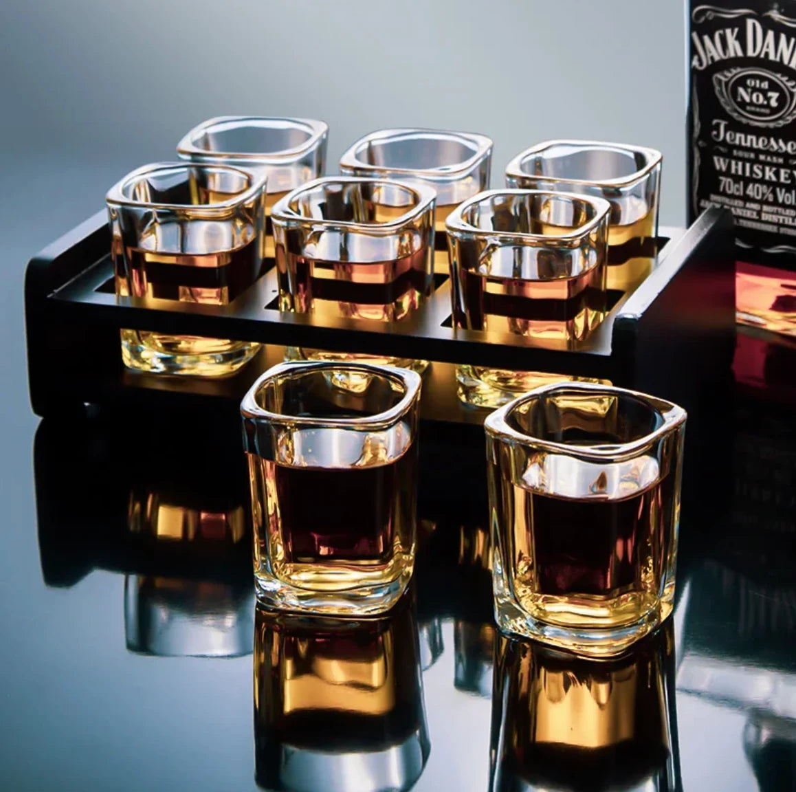 Set of shot glasses on a wooden stand with a Jack Daniel's bottle in the background.