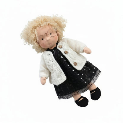 Toy doll with blonde hair, glasses, and a black dress with a white cardigan on a white background