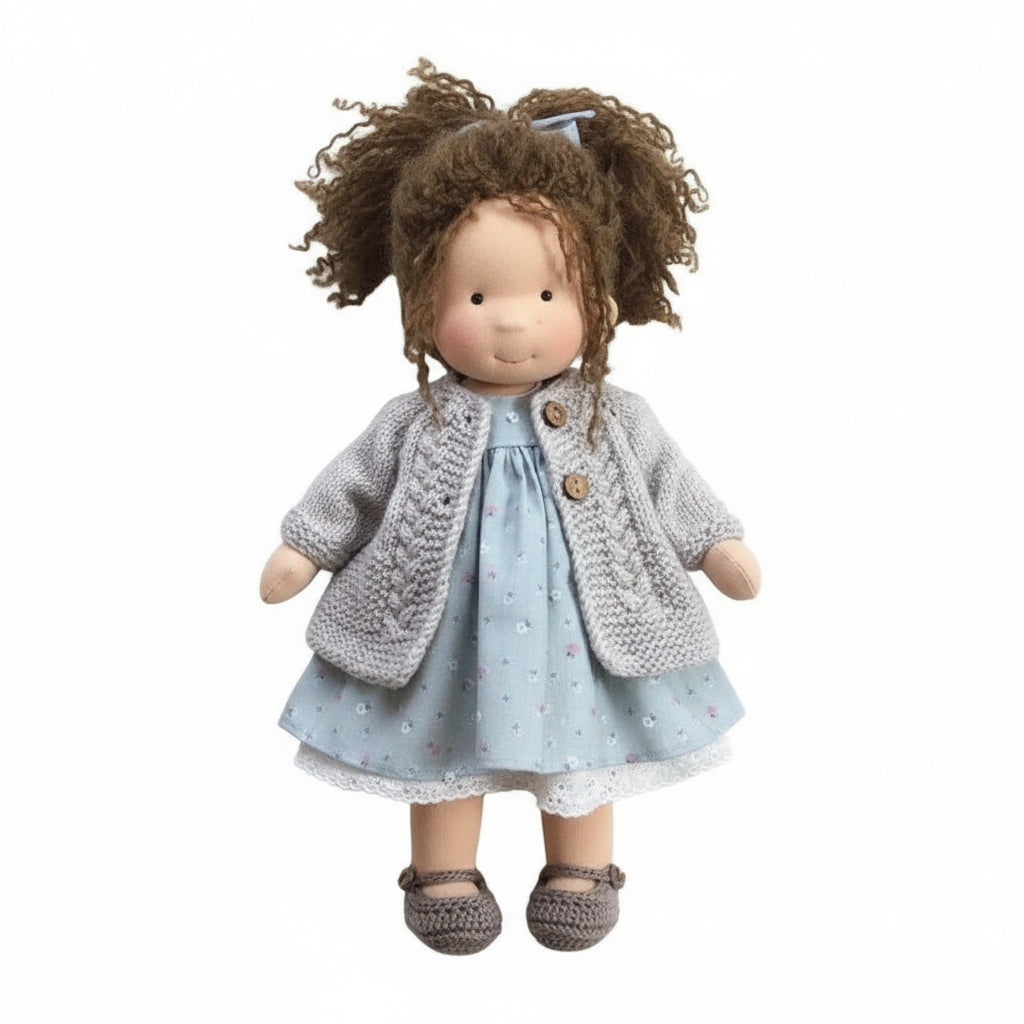 Doll wearing a gray knitted cardigan and light blue dress on a white background