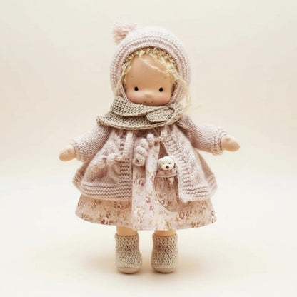 Toy doll wearing a knitted outfit on a light background