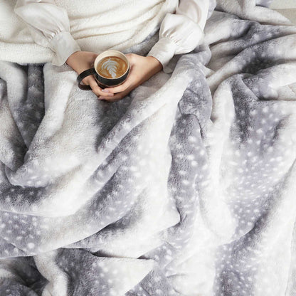 Person holding a coffee cup wrapped in a soft, patterned blanket