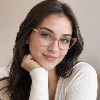 Josh & Tate - FelineFrame™ Blue Light Glasses - A woman with long dark brown hair wearing rose gold cat-eye eyeglasses and a cream ribbed knit top, resting her chin on her hand against a soft beige background.