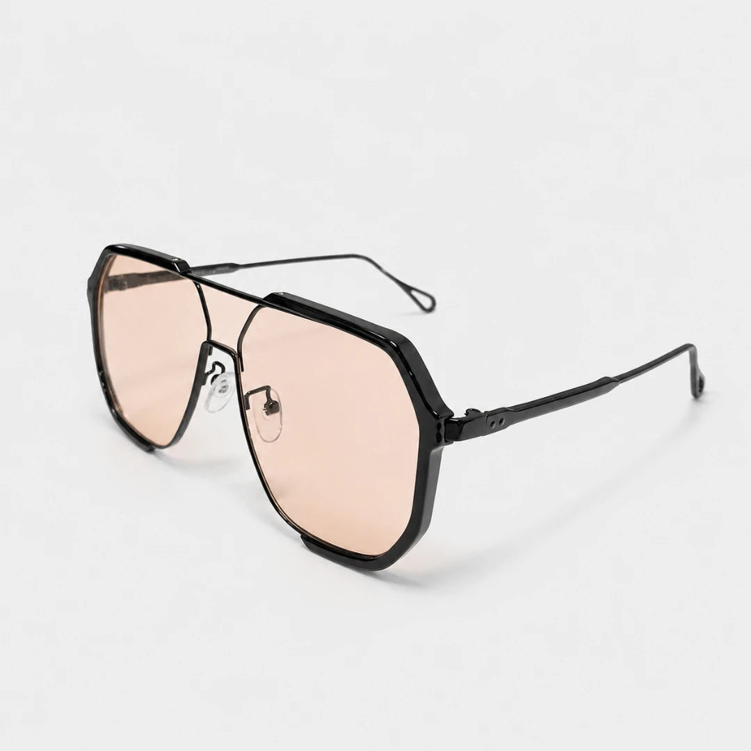 Josh & Tate - FlexFrame™ Bold Frame Glasses - Black aviator-style sunglasses with oversized angular lenses in a translucent peach-pink tint, shown on a clean white background.