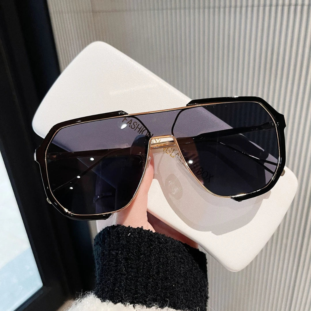 Josh & Tate - FlexFrame™ Bold Frame Glasses - Black sunglasses held by a hand with a blurred background