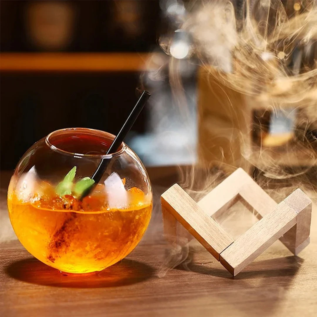 Josh & Tate - Floating Sphere Glass (16oz / 500mL) - Glass bowl with an orange liquid and a wooden coaster on a wooden surface