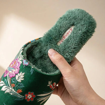 Josh & Tate - FloraStep™ Satin Fur-Lined Slipper - Green embroidered slipper with fluffy interior held by a hand against a beige background
