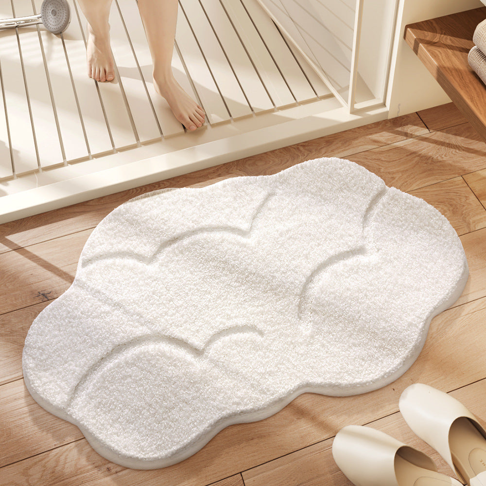 White cloud-shaped bath mat on a wooden floor with a bathtub in the background.