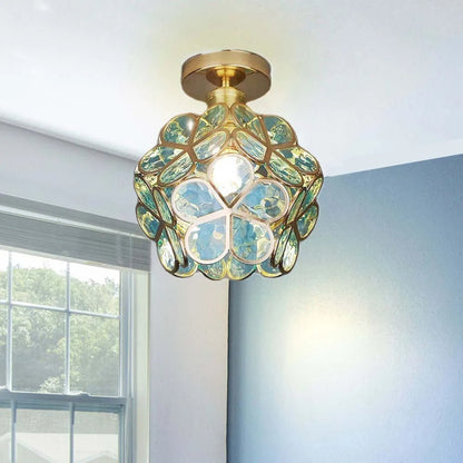 Decorative ceiling light fixture with green and gold design in a room with a window.