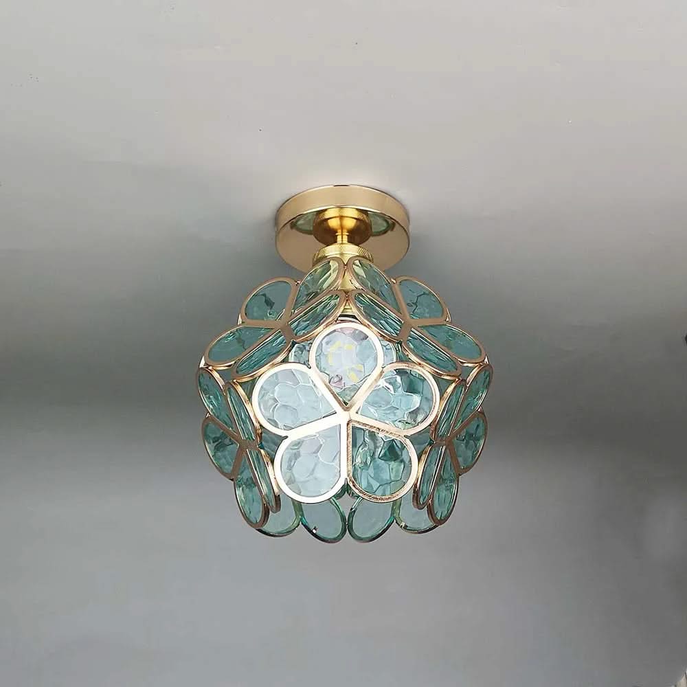 Ceiling light fixture with green glass and gold accents on a neutral background