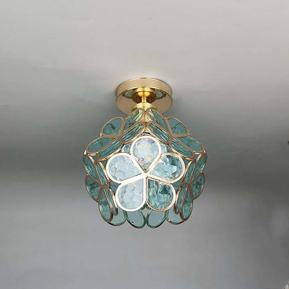 Ceiling light fixture with green glass and gold accents on a neutral background