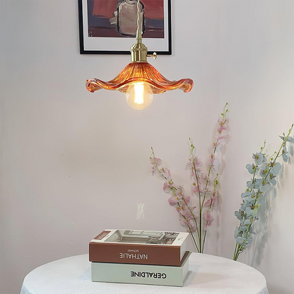 Decorative pendant light with a warm glow above books on a table, with flowers in the background.