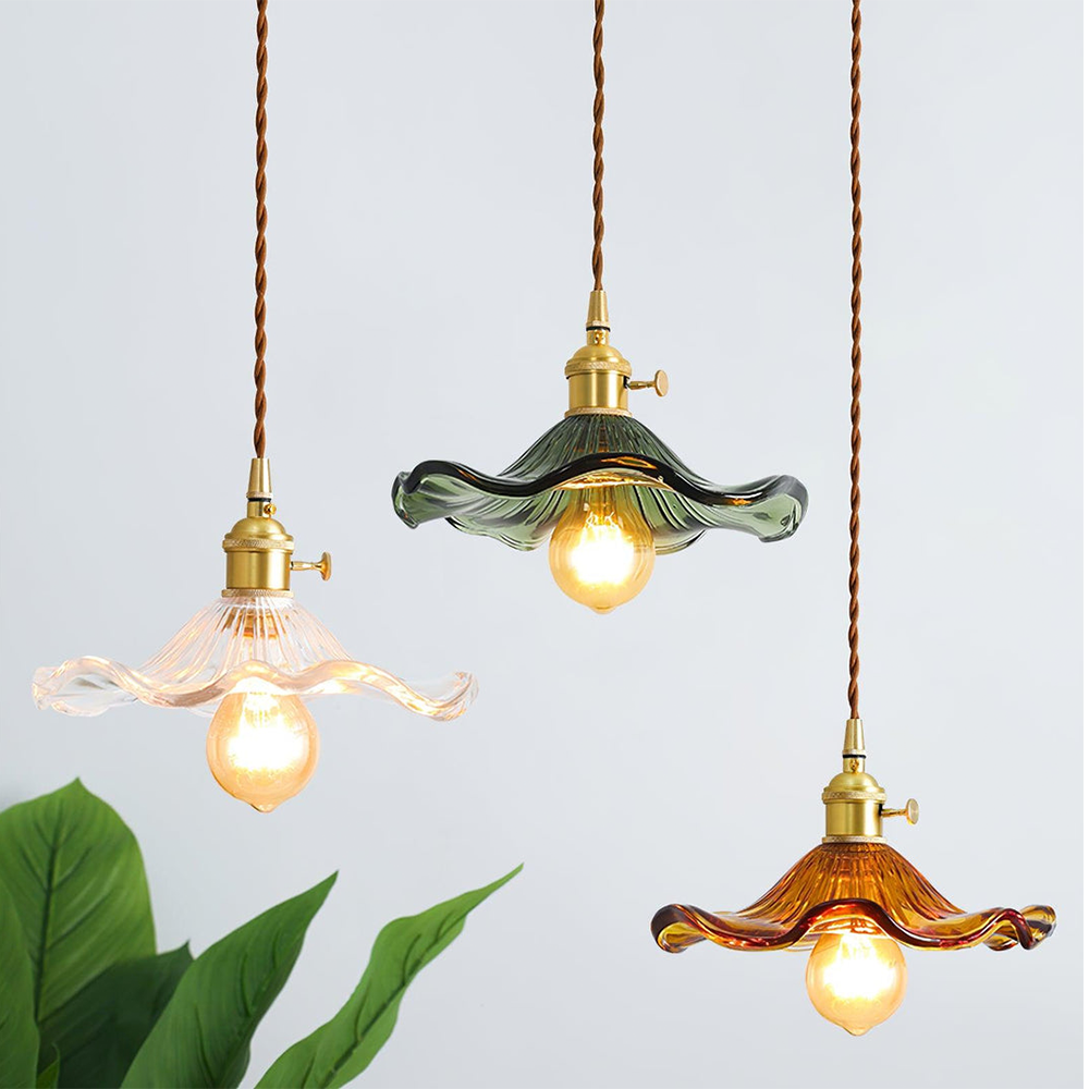 Three pendant lights with glass shades and exposed bulbs on a light gray background.