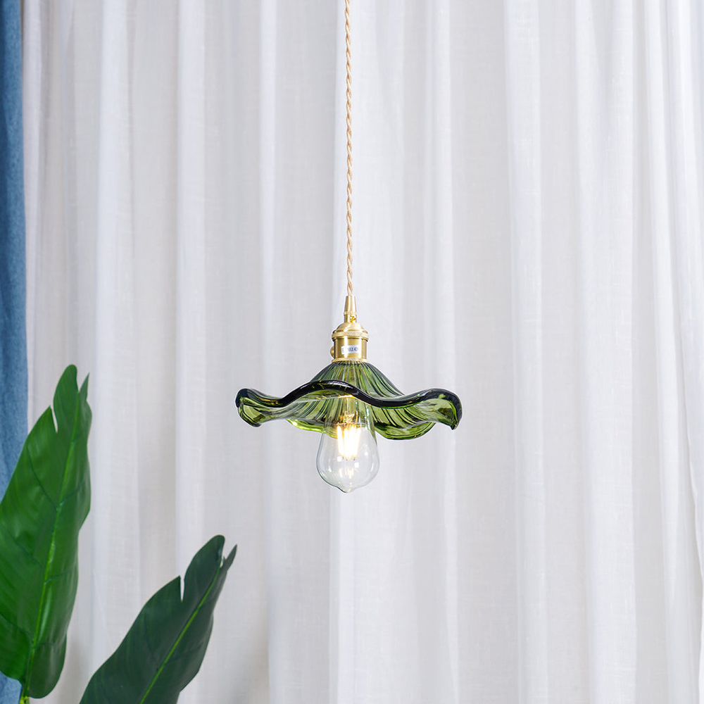 Green pendant light with a white bulb against a white curtain background