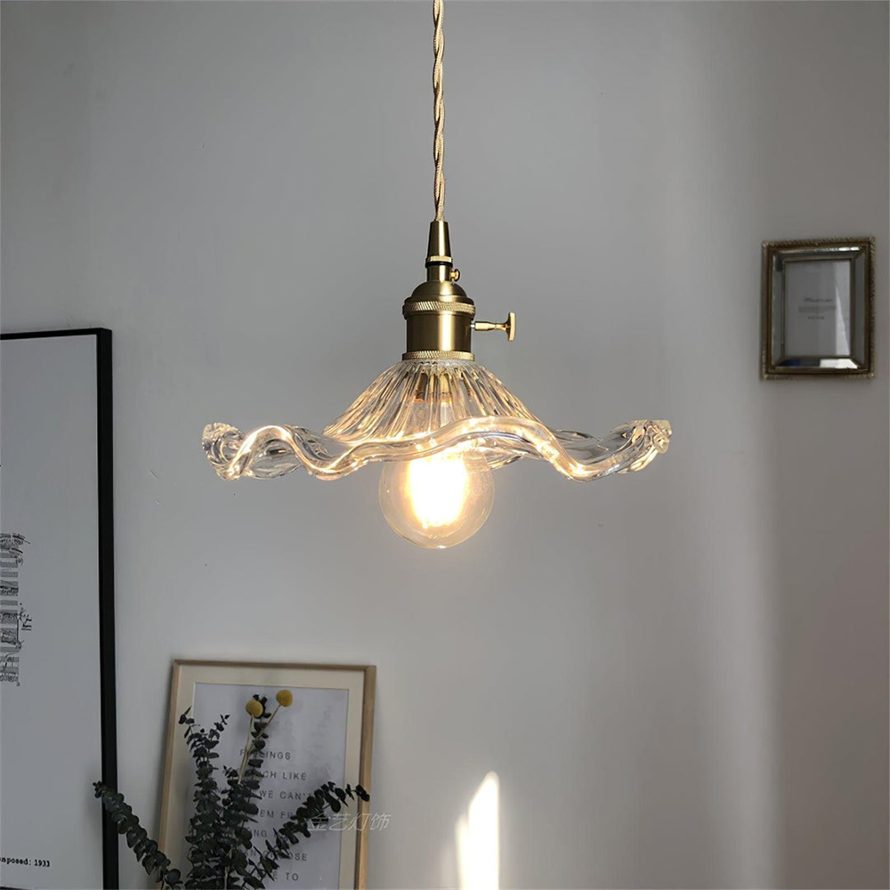 Glass pendant light with gold fixture on a gray wall