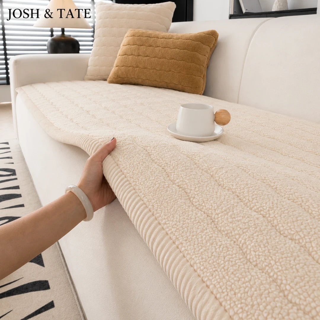 Josh & Tate - FluffLayer™ Plush Sofa Pad - Person holding a textured beige throw blanket on a sofa with 'JOSH & TATE' branding.