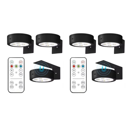 Set of four black outdoor wall lights with remote controls on a white background