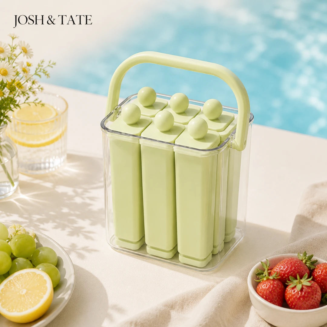 Josh & Tate - FrostPop™ 2-in-1 Popsicle Maker - Green popsicle mold with a handle on a table by a pool, surrounded by lemons, grapes, and strawberries.