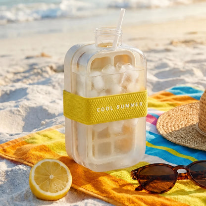 Josh & Tate - FrostPour™ 2-in-1 Ice Cube Tray & Drinking Bottle - Clear bottle with yellow band labeled 'Cool Summer' on a beach setting with sunglasses and lemon.