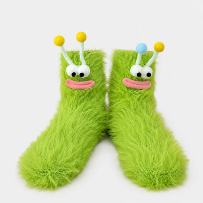 Josh & Tate - FuzzBuddy™ Cozy Socks - A pair of bright lime green fuzzy socks shaped like cartoon alien feet, with white embroidered eyes, pink stitched mouths, and antennae topped with yellow and blue balls, shown on a light gray background.