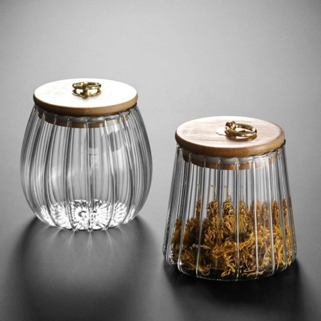 Two glass containers with wooden lids on a gray background
