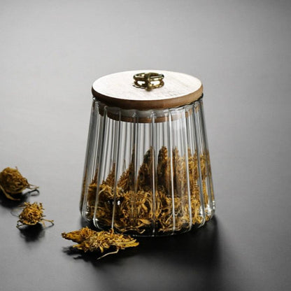 Glass container with dried herbs and a wooden lid on a gray background