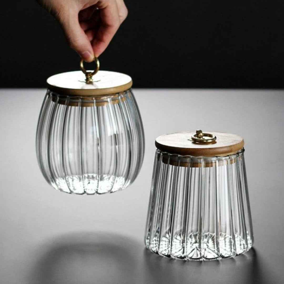 Two glass canisters with wooden lids on a gray surface.