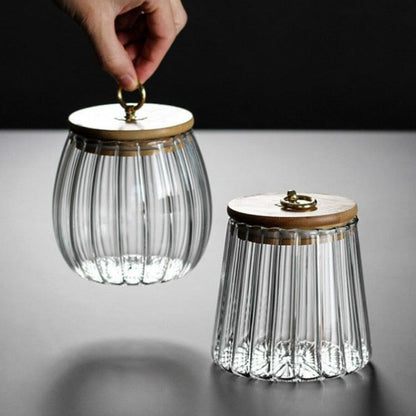 Two glass canisters with wooden lids on a gray surface.