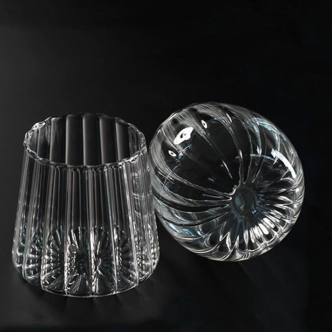 Two clear glass candle holders on a black background
