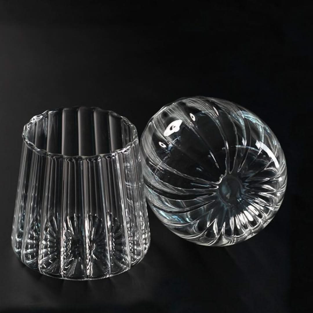 Two clear glass candle holders on a black background