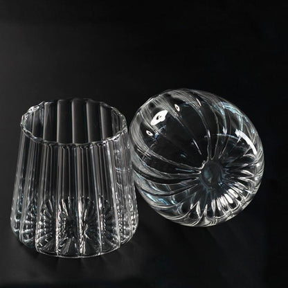 Two clear glass candle holders on a black background