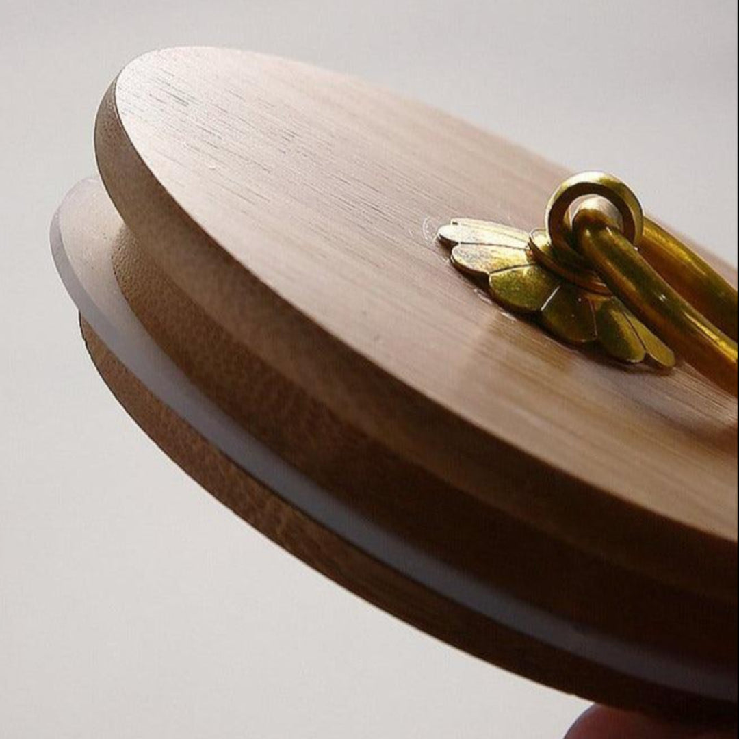 Wooden lid with a decorative handle on a light gray background