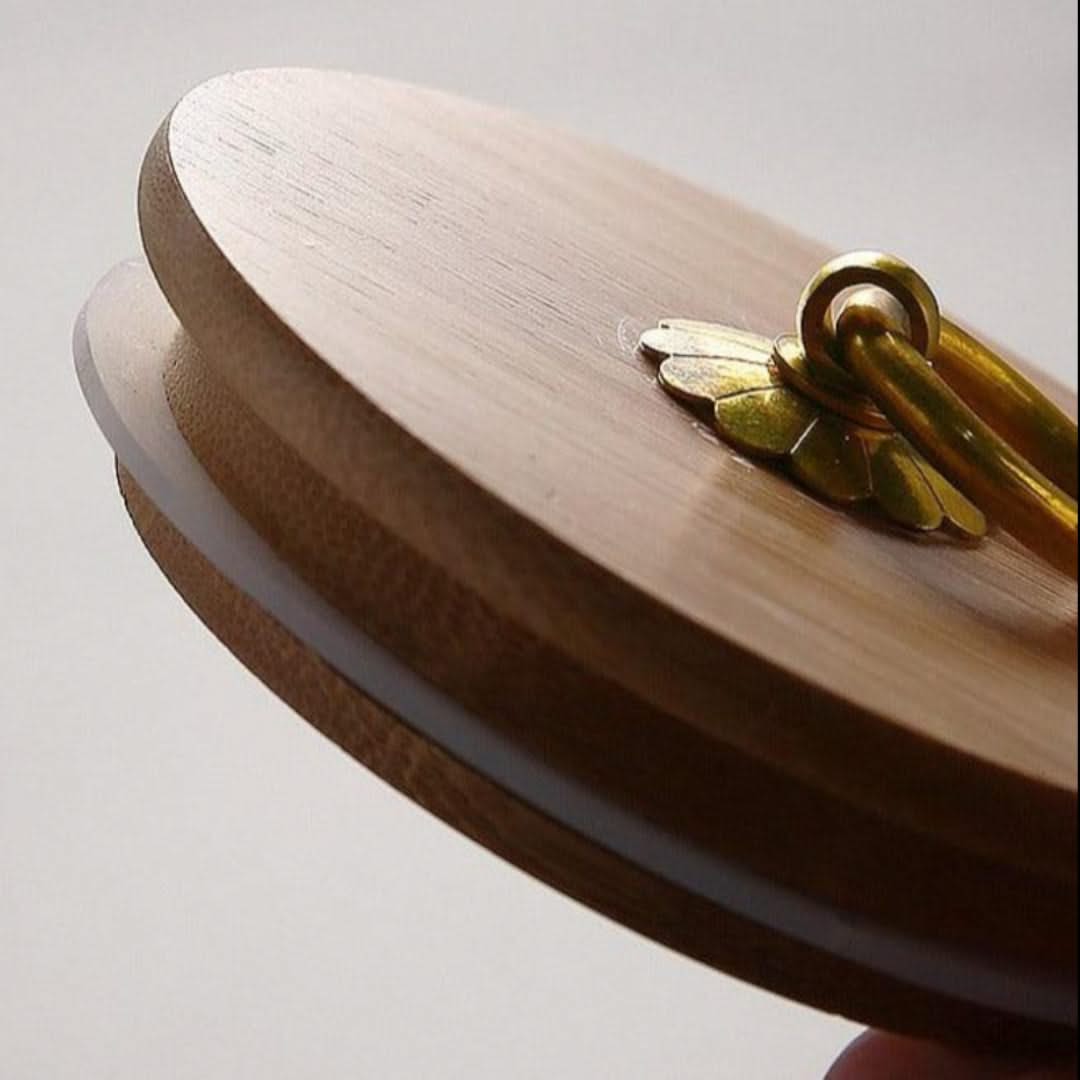 Wooden lid with a decorative handle on a light gray background