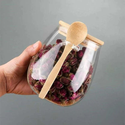 Josh & Tate - Glass Storage Jar with Spoon - Glass jar with dried flowers and a wooden spoon on a gray background