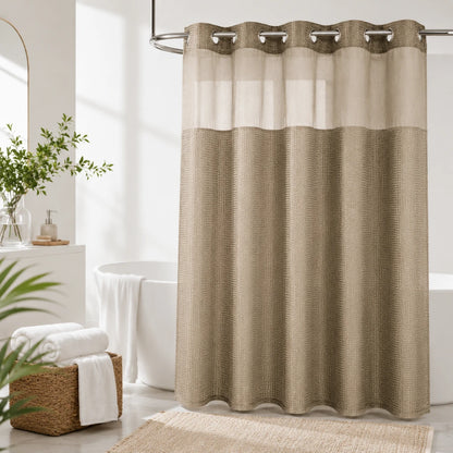 Josh & Tate - GlideCurtain™ No-Hook Shower Curtain - A beige and white grommet-top shower curtain hanging in a bright, modern bathroom with a white tub, woven basket, and greenery.