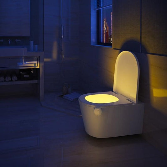 Bathroom with a glowing toilet seat in a dark setting