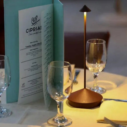 Dinner table setting with wine glasses, a menu, and a candle.