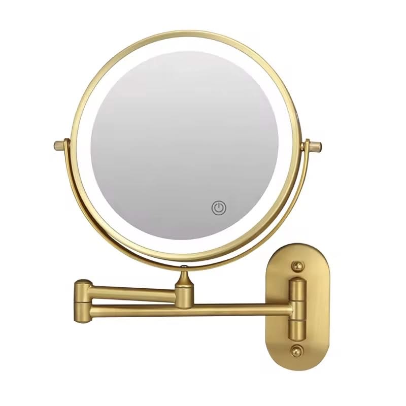 Gold wall-mounted makeup mirror with a light on a white background
