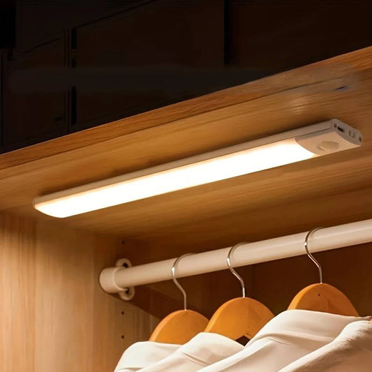 Josh & Tate - GlowMotion Motion Sensor Lamp - Under-cabinet light fixture illuminating clothes in a wooden cabinet.