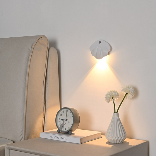 Decorative items on a nightstand including a clock, book, and vase with flowers.