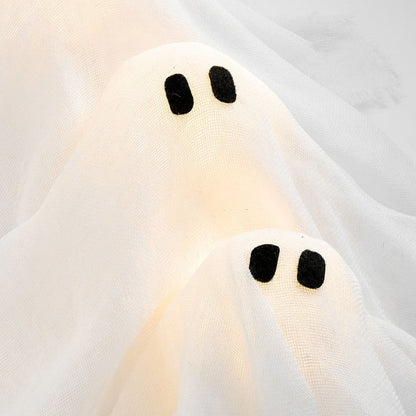 White ghost-shaped pillow with black eyes on a white background