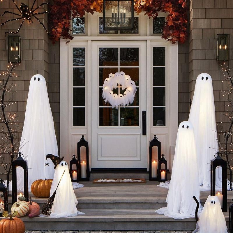 Halloween decorations on a front porch with ghosts, pumpkins, and candles.