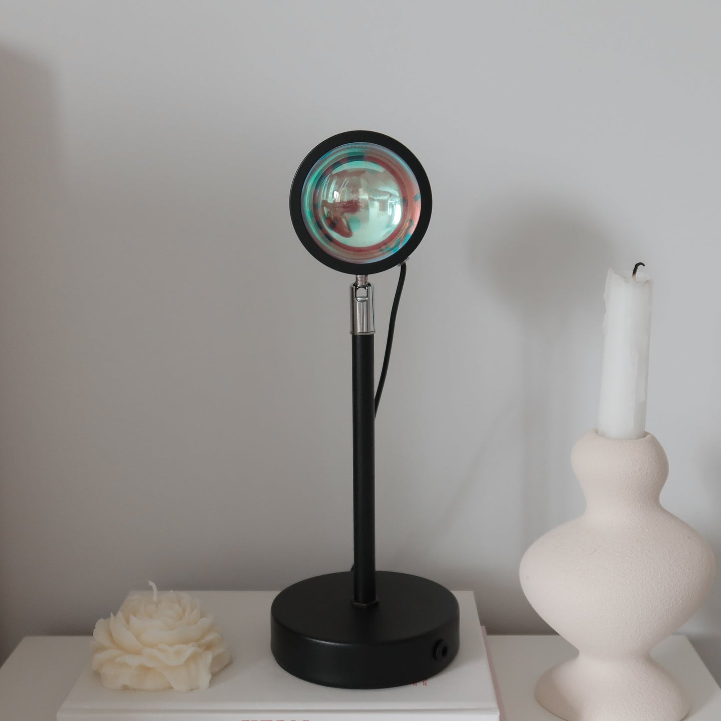 Black lamp with round glass shade on a white surface against a plain wall