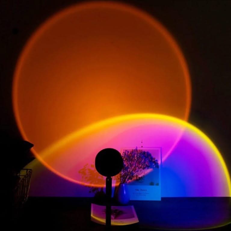 Colorful light projection on a dark background with a small plant and decorative item.