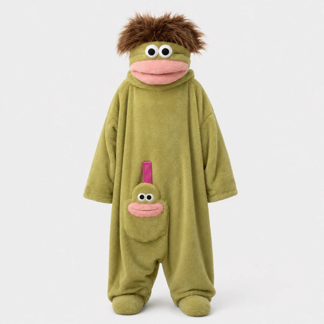 Josh & Tate - GoofSuit™ Big Mouth Monster Onesie - A plush monster costume jumpsuit in olive green with a brown furry hair accessory, pink mouth details, and a smaller matching face patch on the pocket, shown against a plain light gray background.