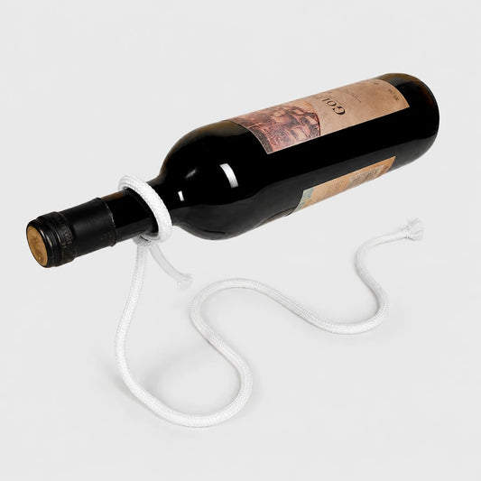 Josh & Tate - GravityKnot™ Floating Wine Holder - A dark glass wine bottle with a white braided rope tied around its neck and draped across the surface, photographed on a clean light gray studio background.