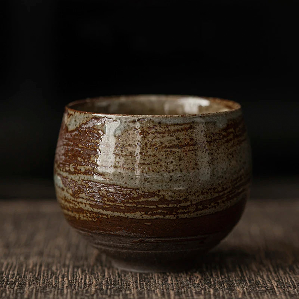 Ceramic cup with brown and beige glaze on a dark background