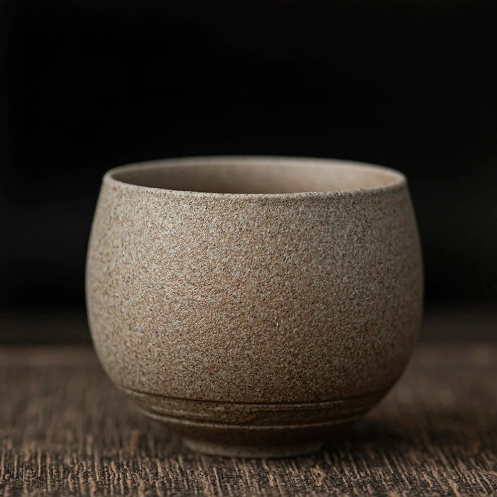 Textured ceramic cup on a wooden surface with a dark background