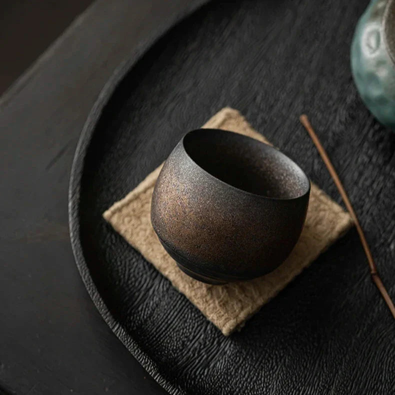 Black ceramic cup on a textured surface with a blurred background
