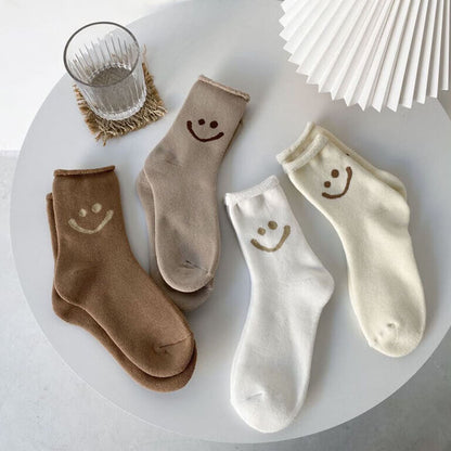 Set of four pairs of socks with smiley face designs on a white surface.